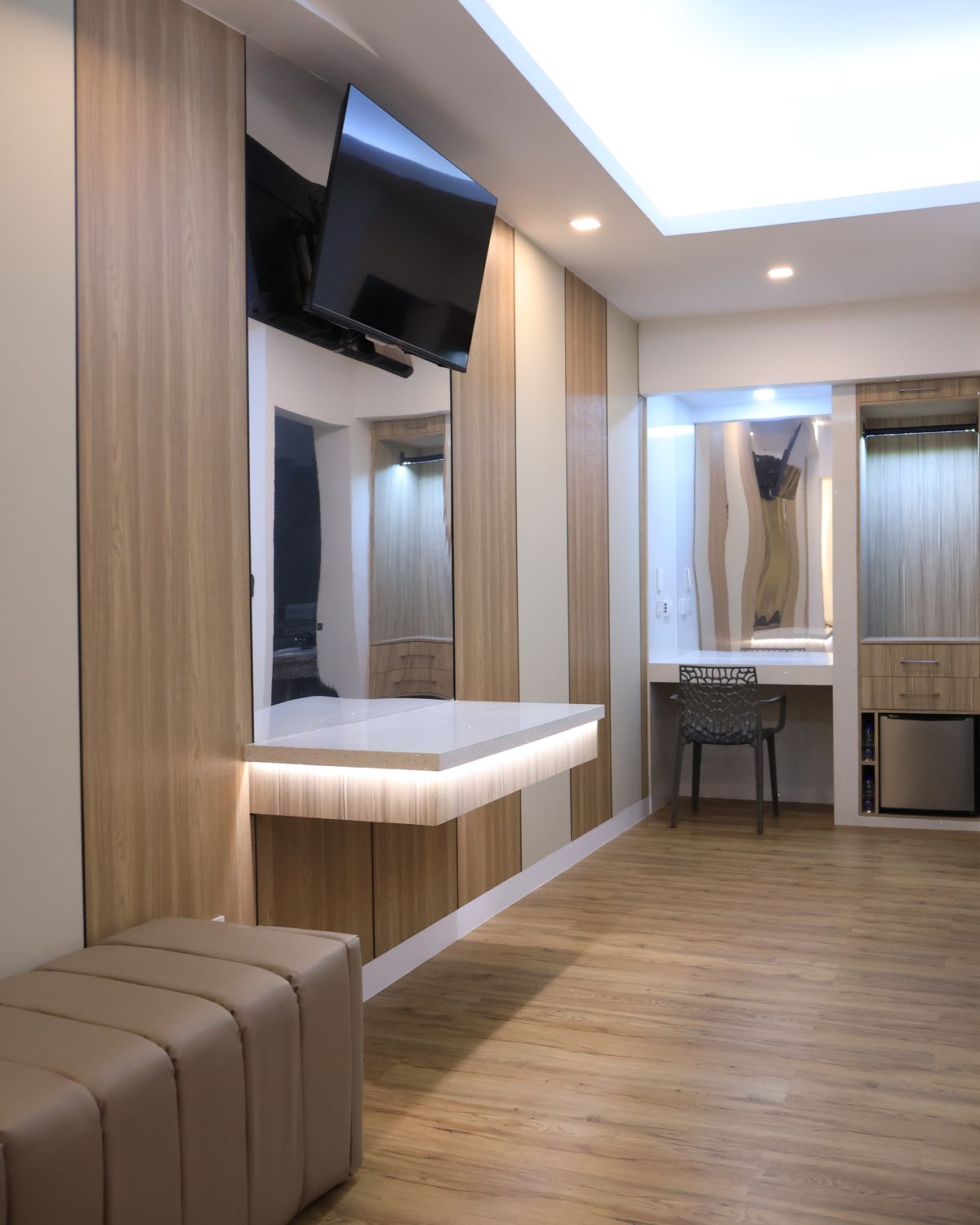 Escritorio iluminado con televisor, espejo, minibar y puf tapizado en la Doble Remodelada