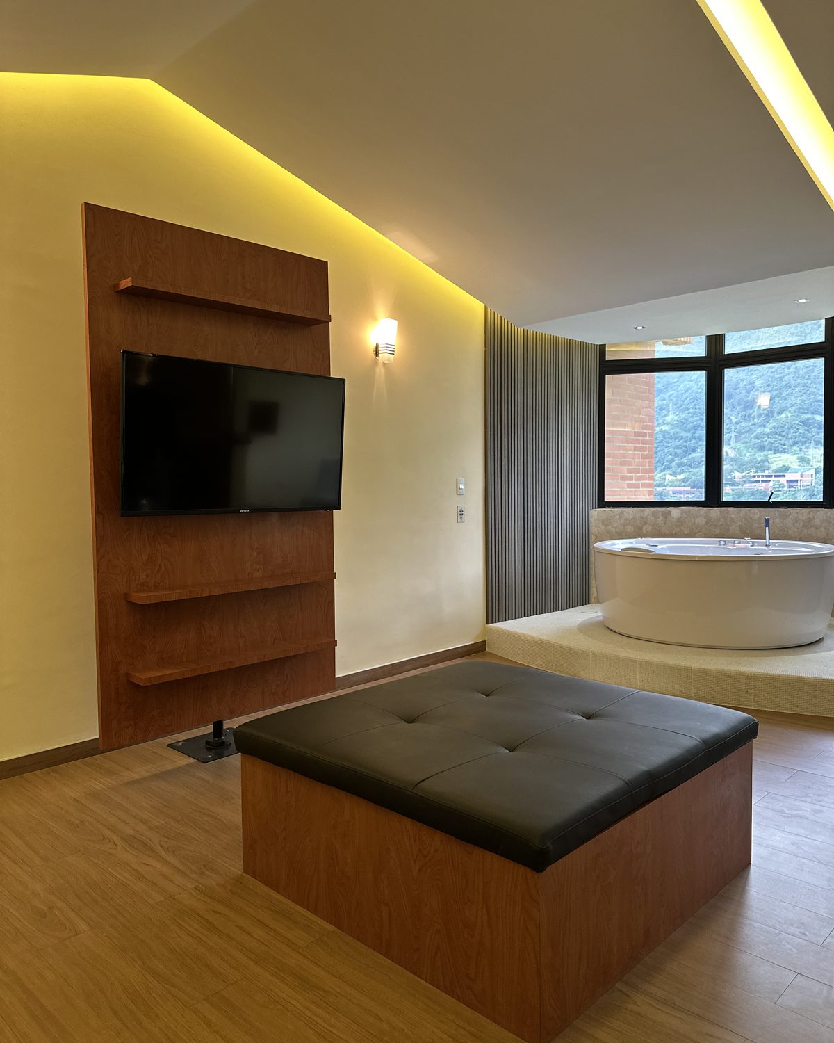 Zen Premium: puf de cuero, televisor en panel de madera y jacuzzi junto a la ventana