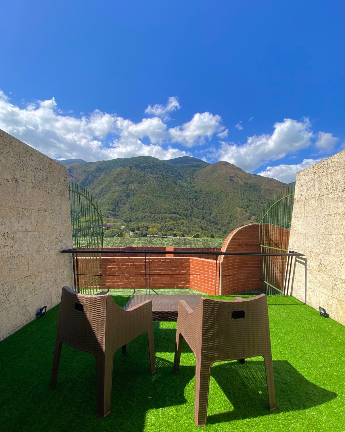 Lounge con Terraza: terraza privada con grama, dos sillas y vista a la montaña
