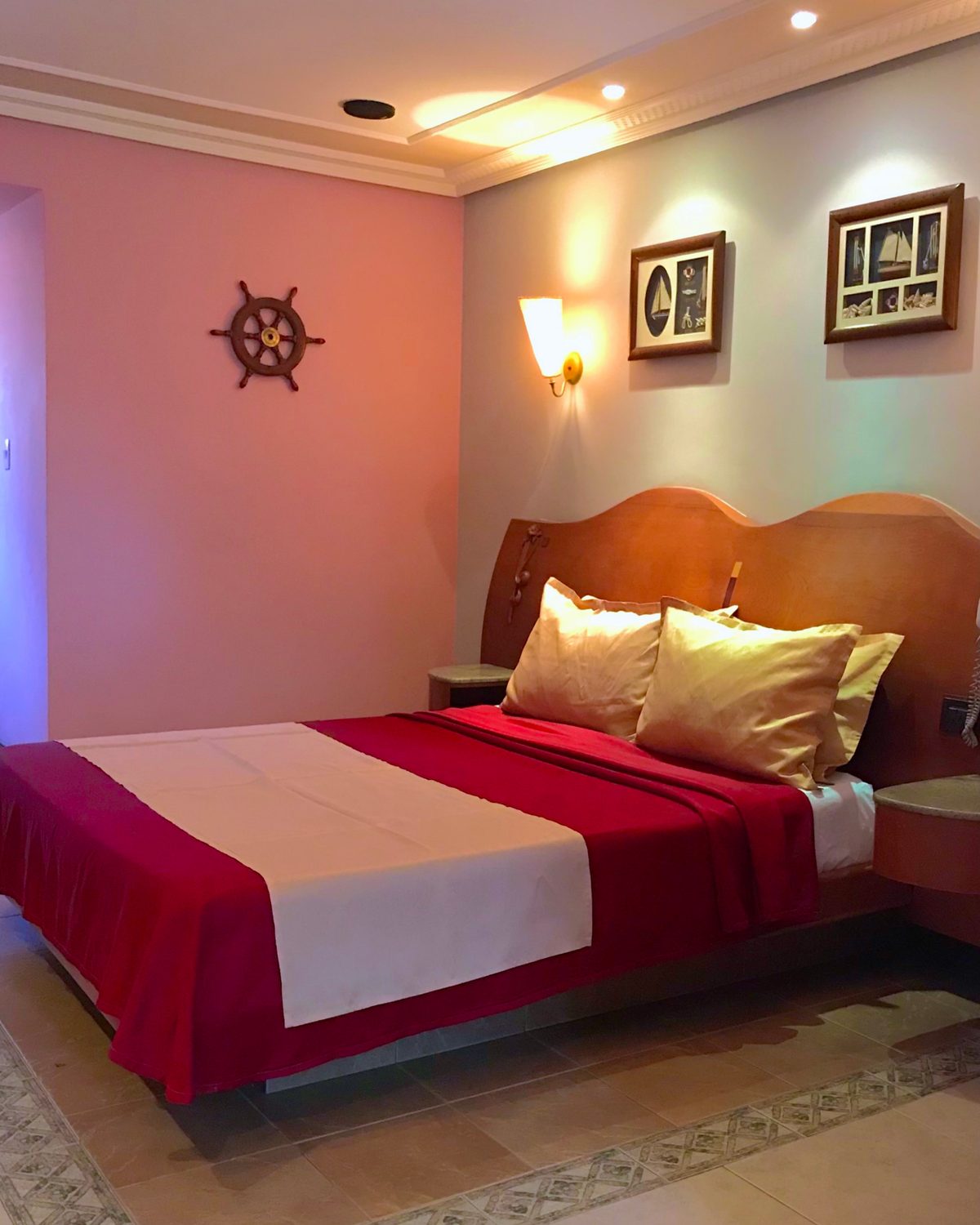 Temática Jacuzzi (Marinera): cama con cubrecama rojo y blanco, timón en la pared y cuadros de barcos