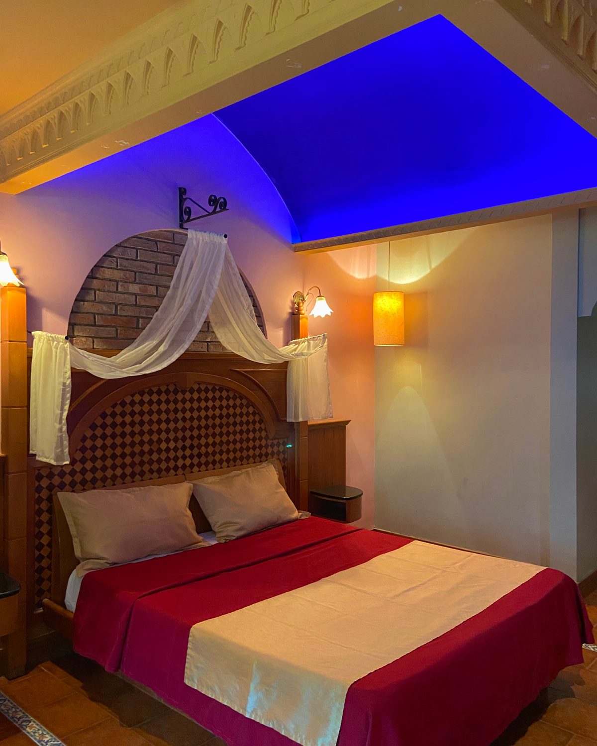 Temática Jacuzzi (Hindú): cama con dosel de tul, cabecero de madera y techo azul iluminado